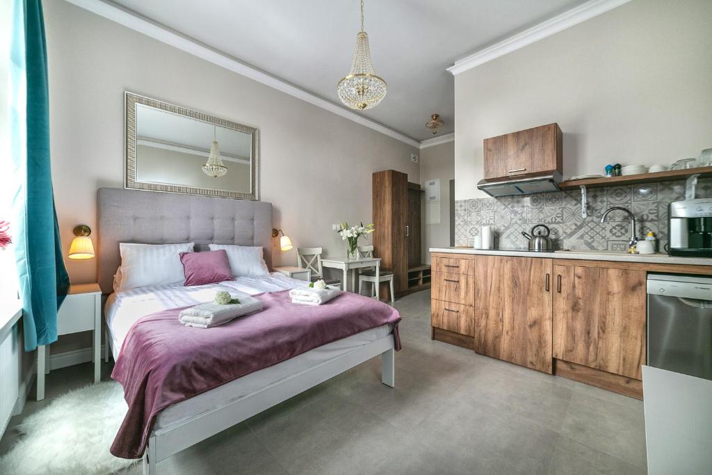 a bedroom with a large bed and a kitchen at Apartamenty Wrona | Wrona Apartments in Krakow