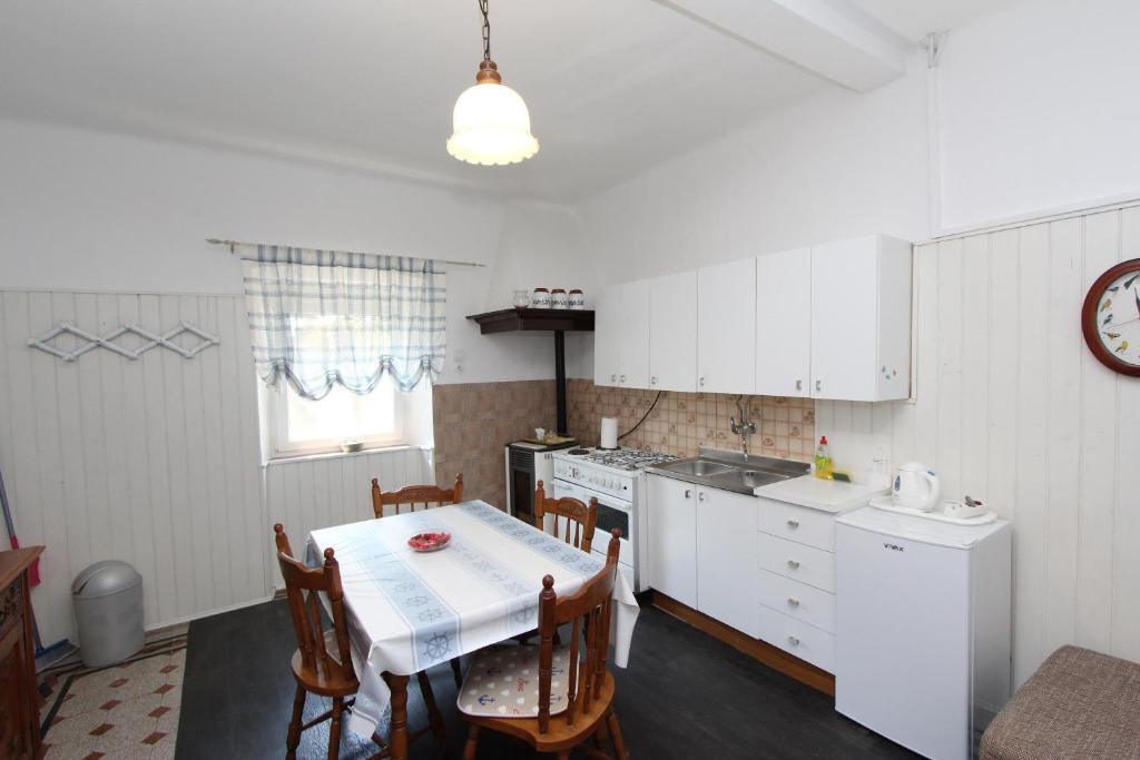 kuchnia ze stołem i krzesłami oraz kuchnia z białymi szafkami w obiekcie Apartments Rosanna w Rovinj