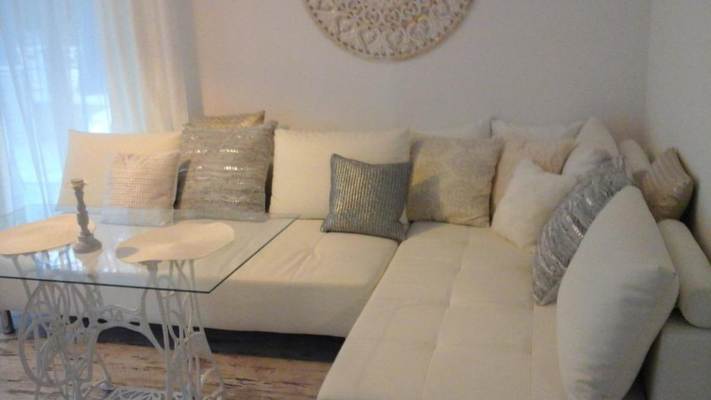 Sofá blanco con almohadas y mesa de cristal en Apartament Leśny en Dziwnówek