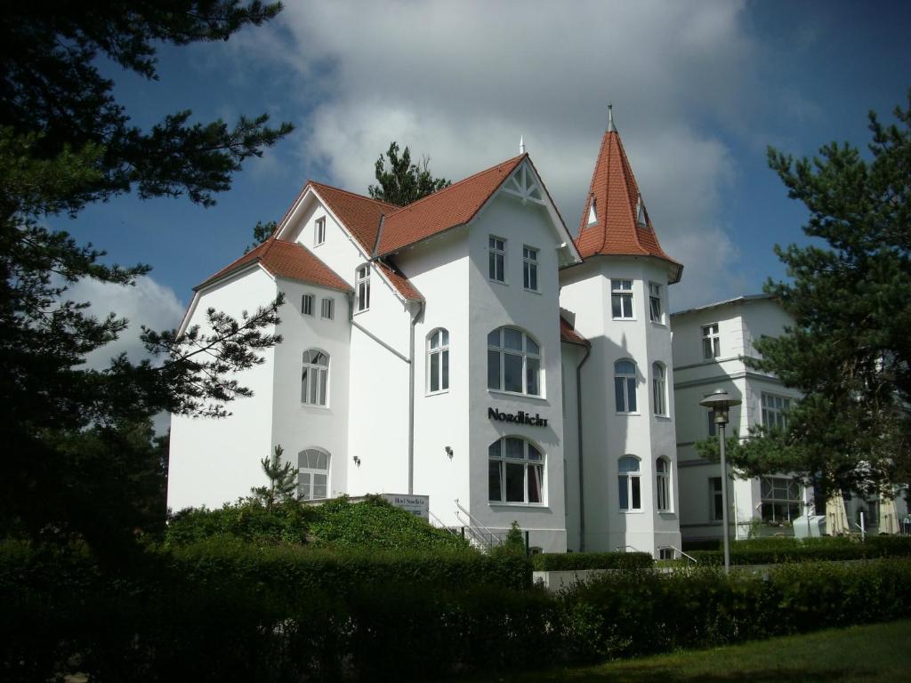 a large white house with a red roof at Hotel Nordlicht in Zinnowitz