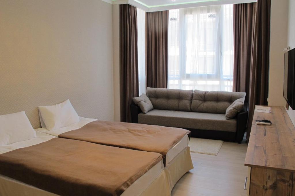 アドレルにあるApartment Na Staroobryadcheskoyのベッド2台とソファが備わるホテルルームです。