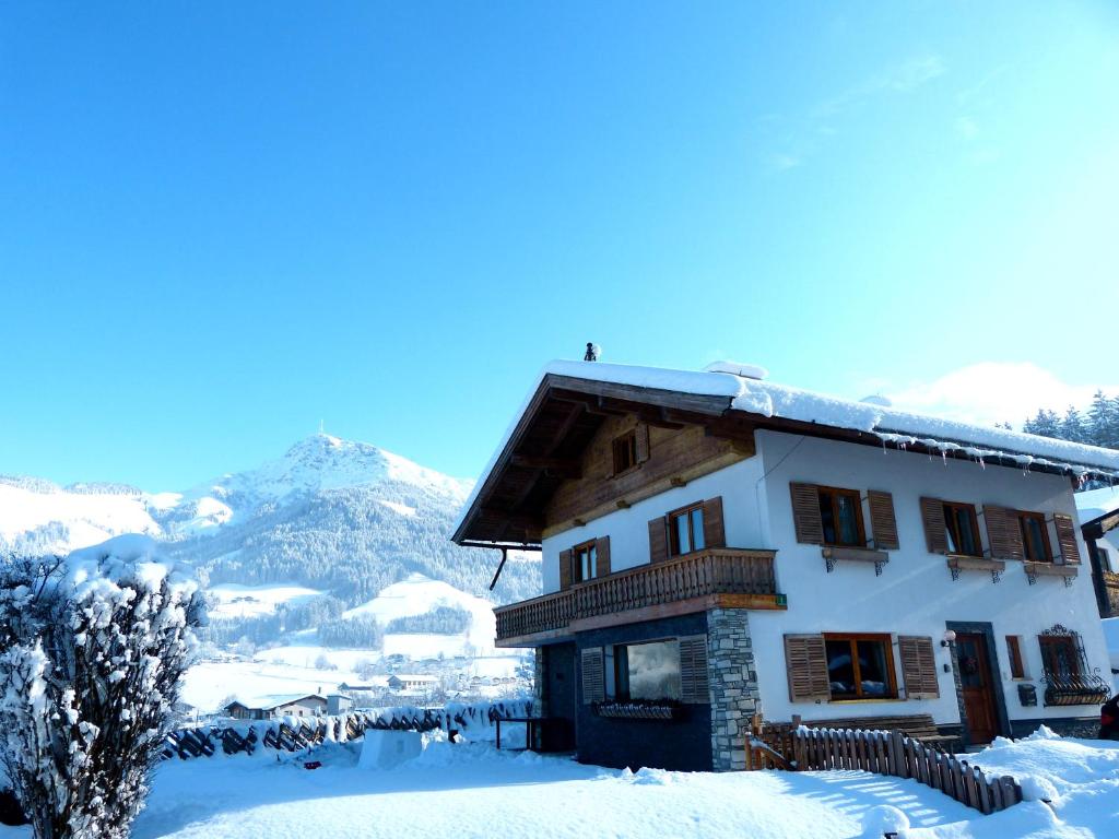 a house covered in snow with mountains in the background at Ferienhaus Rauter in Oberndorf in Tirol