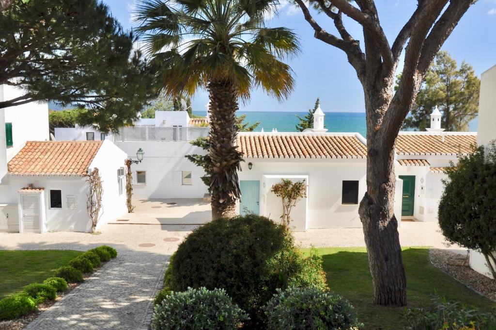 a house with a palm tree and the ocean in the background at Aquamarine - Gemstone Getaway in Vale do Lobo