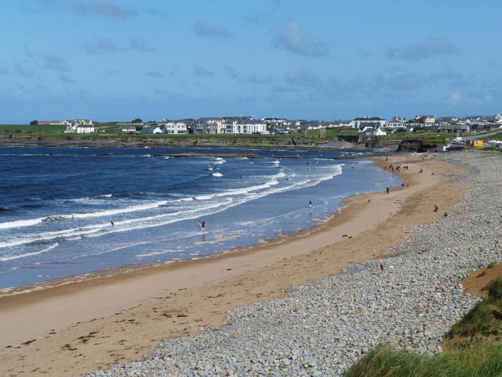 a beach with people walking on the sand and the ocean at Sheila's View - Spanish Point, Co. Clare in Spanish Point