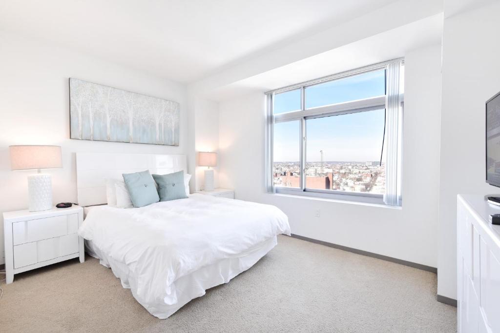 a white bedroom with a white bed and a window at Global Luxury Suites at Kendall West in Cambridge