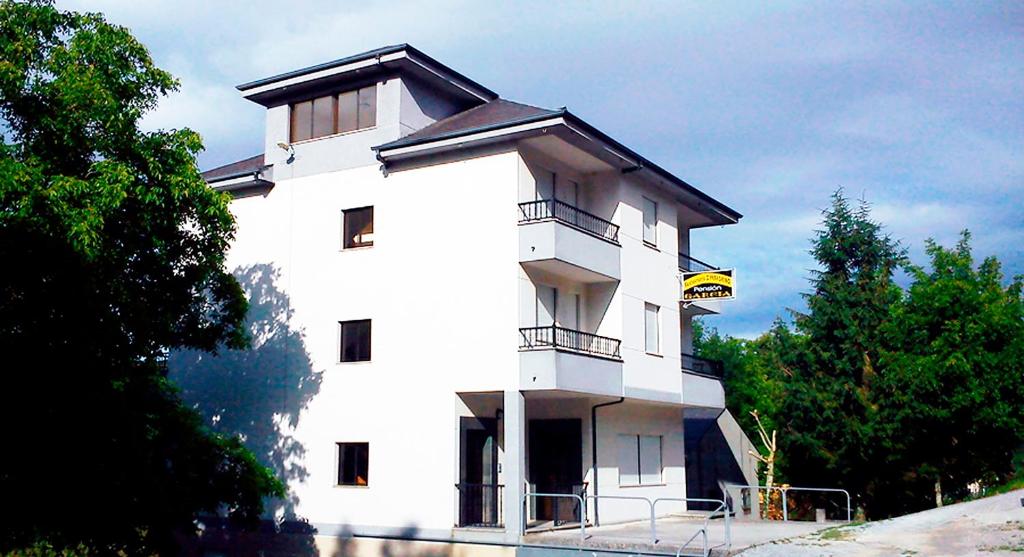 a white building with a balcony on top of it at Pensión Garcia in Treacastela