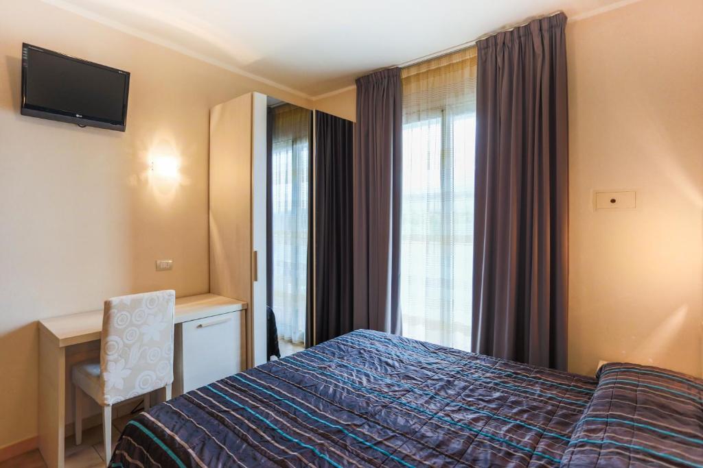 ein Hotelzimmer mit einem Bett, einem Schreibtisch und einem Fenster in der Unterkunft Hotel Caribia Pinarella in Cervia
