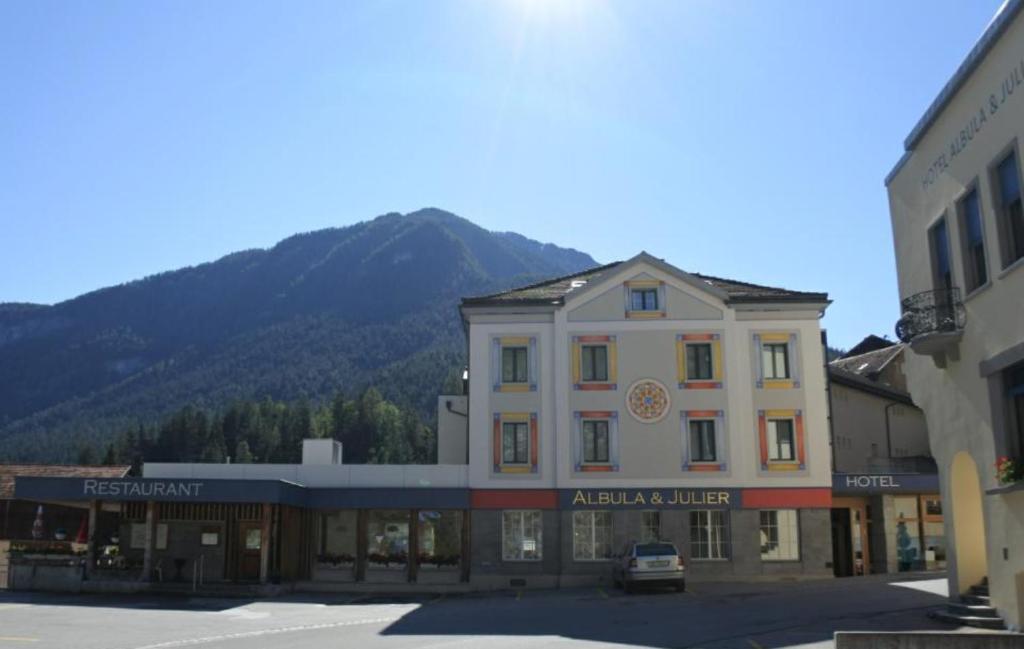 ein Gebäude in einer Stadt mit einem Berg im Hintergrund in der Unterkunft Hotel Albula & Julier in Tiefencastel