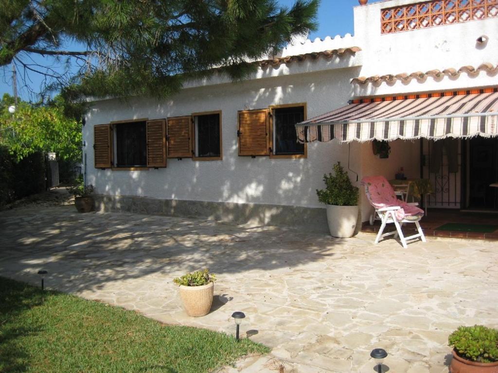 a house with a patio and a chair in front of it at Chalet con piscina in L'Ampolla