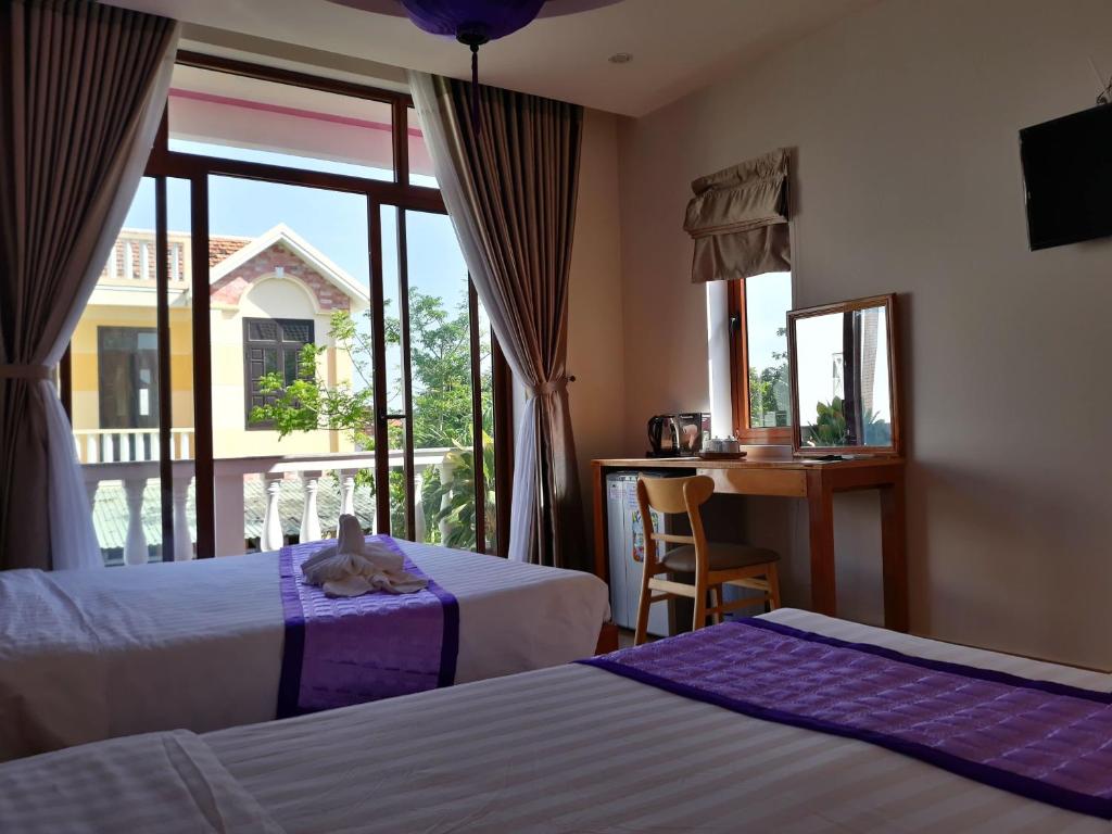 a hotel room with two beds and a window at Pink house Homestay in Hoi An