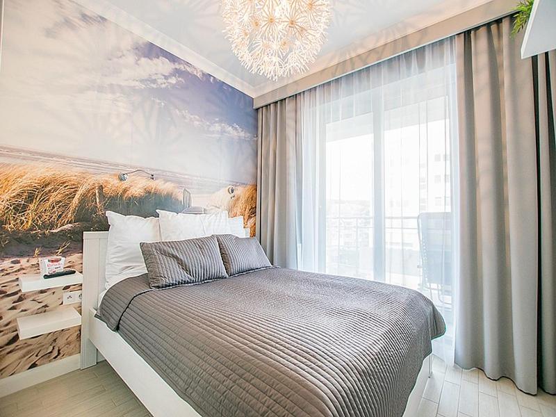 1 dormitorio con 1 cama con una pintura en la pared en Promenada Gwiazd 28 Apartament Perła z parkingiem, en Międzyzdroje