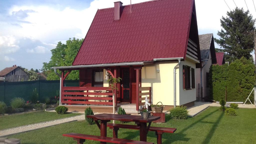 ein kleines Haus mit einem roten Dach und einem Picknicktisch in der Unterkunft Levendula Ház in Lipót
