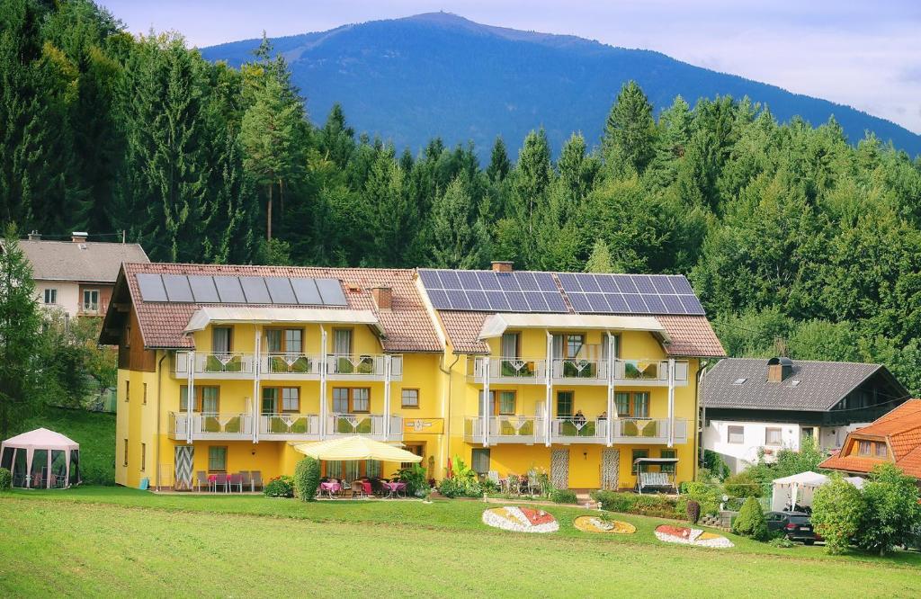 ein gelbes Gebäude mit Sonnenkollektoren auf dem Dach in der Unterkunft Gästehaus Götz in Drobollach am Faakersee