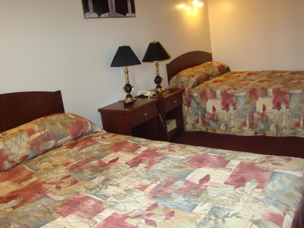 ein Hotelzimmer mit 2 Betten und einem Tisch mit Lampen in der Unterkunft Hotel Quartier Latin in Montreal