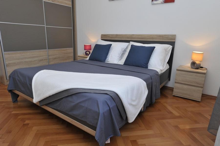 1 dormitorio con 1 cama grande con almohadas azules y blancas en Apartman Mirakul, en Split