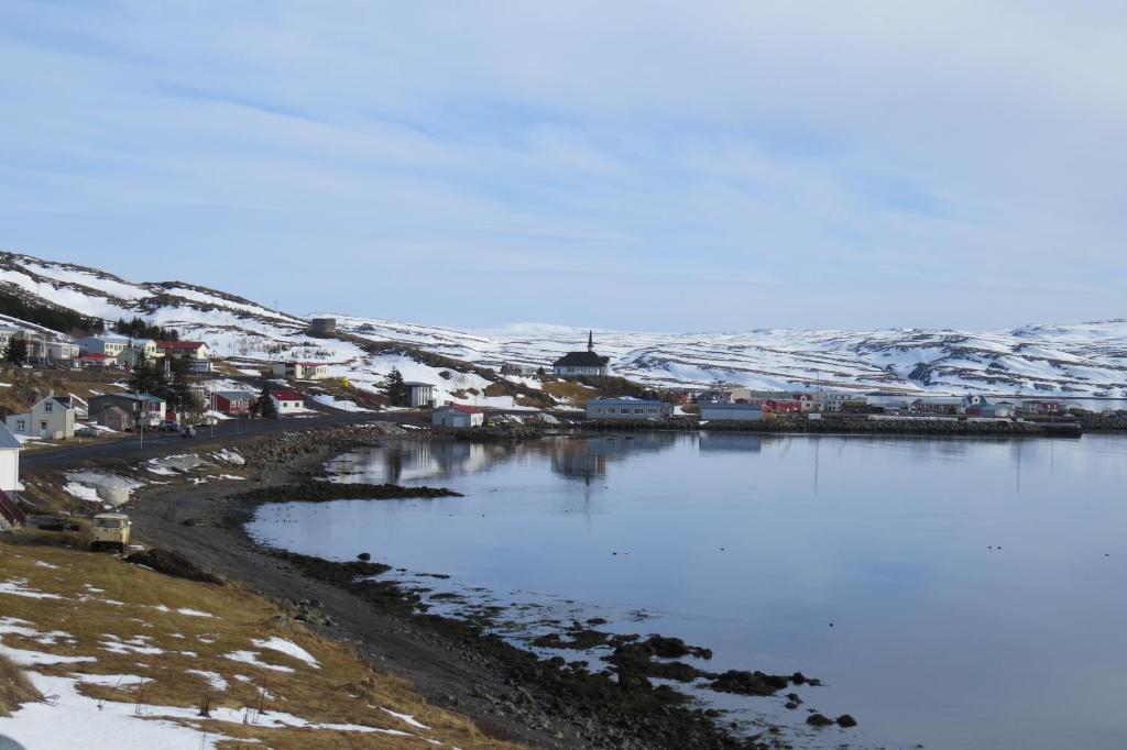 a town with snow covered hills and a body of water at Beautiful house just 50 m from the sea in Hólmavík
