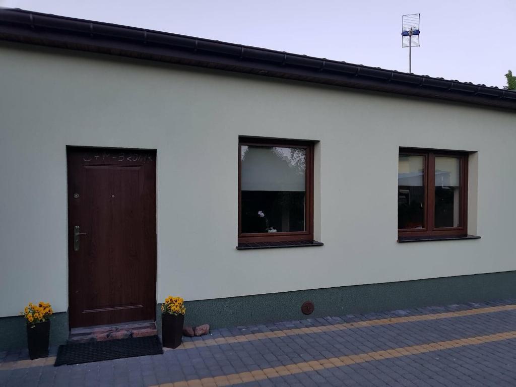 a white house with a brown door and two windows at Kwatera prywatna in Augustów