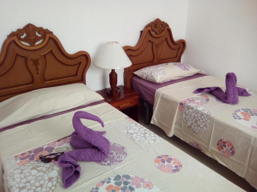 2 Betten in einem Zimmer mit lila Handtüchern darauf in der Unterkunft Carlos y Rosa in Puerto de la Cruz