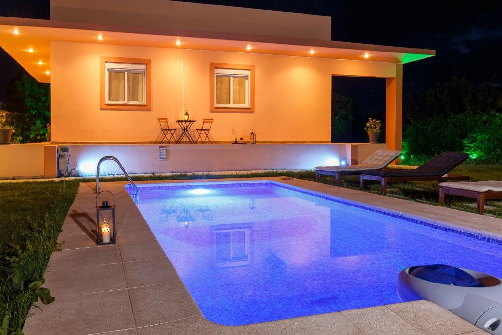 a swimming pool in front of a house at night at Summer Breeze Villa in Afantou