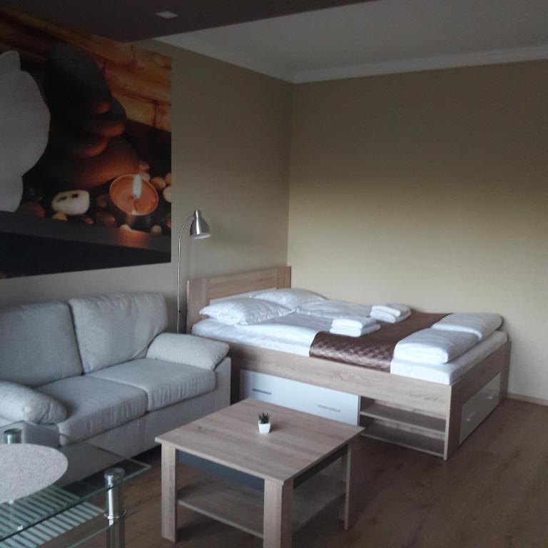 uma sala de estar com uma cama e um sofá em Stúdió 18 Apartman em Kazincbarcika