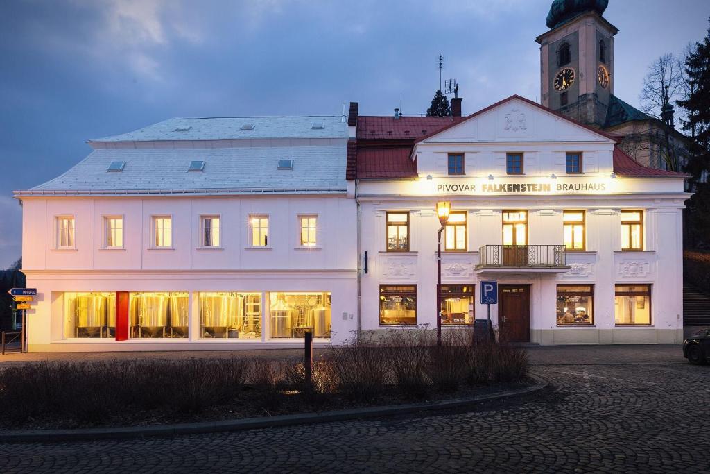 un gran edificio blanco con luces encendidas en Pivovar Falkenštejn en Krásná Lípa