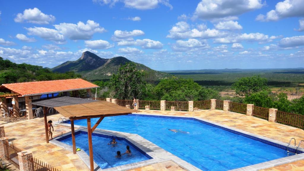 a swimming pool with a mountain in the background at Fazenda Hotel Pedra dos Ventos in Quixadá