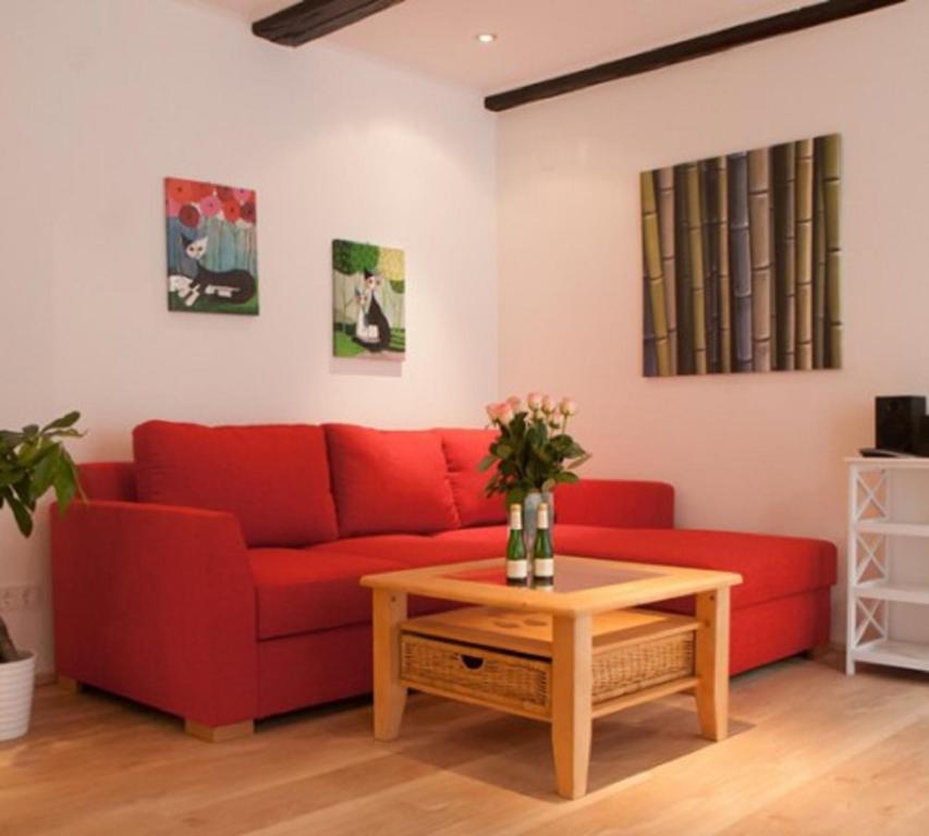 a red couch in a living room with a coffee table at Aufhauser Hof Regensburg in Regensburg