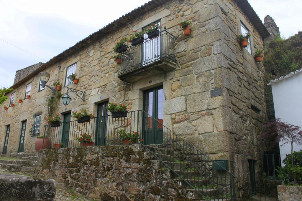 un antiguo edificio de piedra con macetas en las ventanas en Casa do Largo do Cais, en Vila Nova de Cerveira