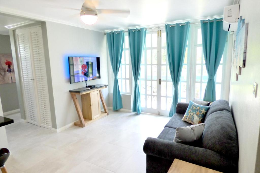 uma sala de estar com cortinas azuis e um sofá em Beach One Bedroom Suite A22 em Ocho Rios