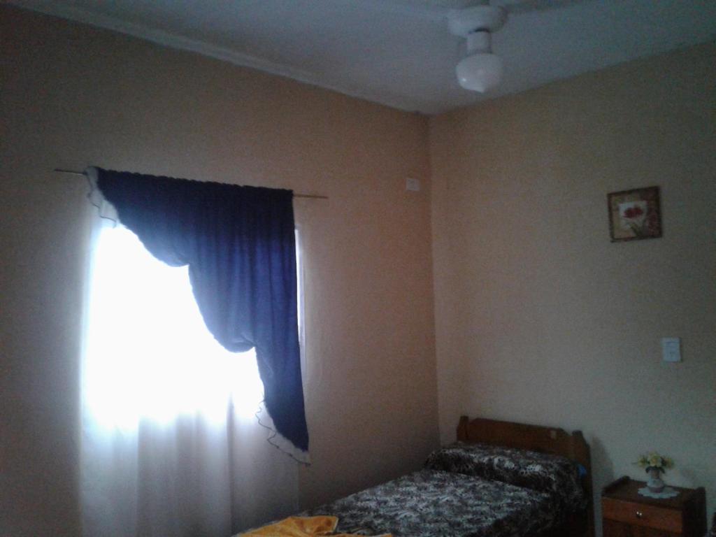 1 dormitorio con cama y cortina azul en Residencial Guadalupe en Termas de Río Hondo