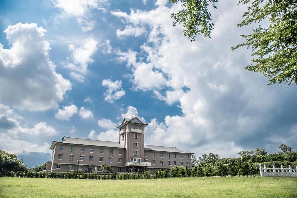 a large building with a clock tower in a field at Jade Garden Hotel in Gukeng