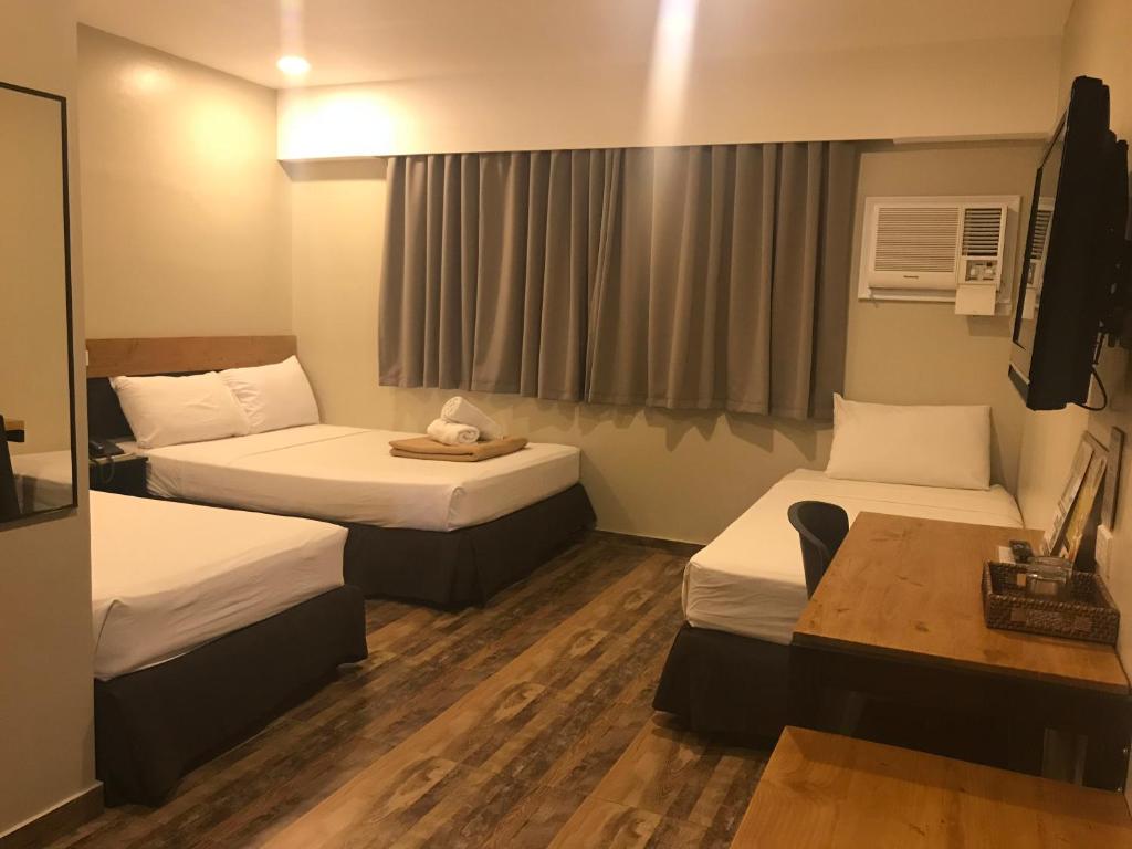a hotel room with two beds and a desk at Cebu R Hotel Capitol in Cebu City