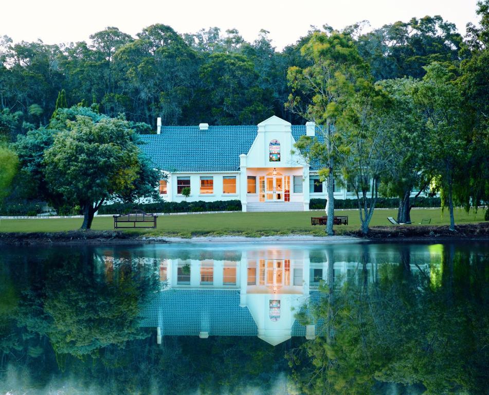 a white house with a reflection in the water at Cape Lodge in Yallingup