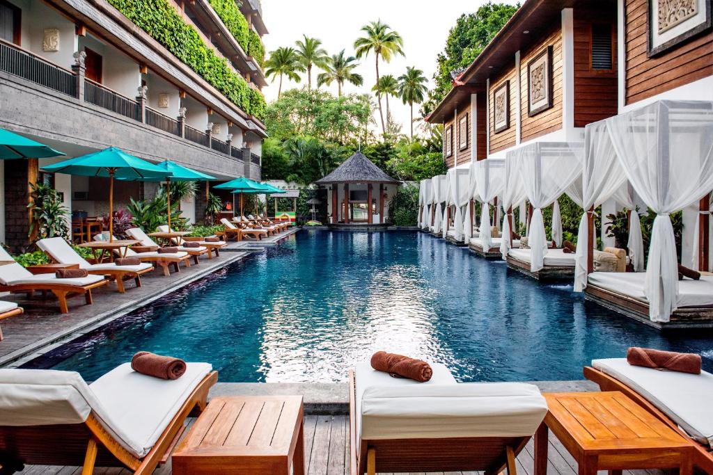 a swimming pool with lounge chairs and a resort at Astagina Resort Villa and Spa in Legian