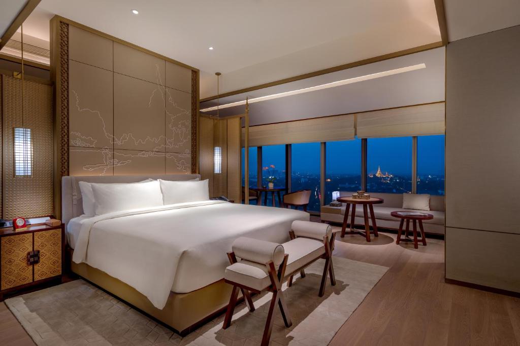 a bedroom with a large bed and a living room at Pan Pacific Yangon in Yangon