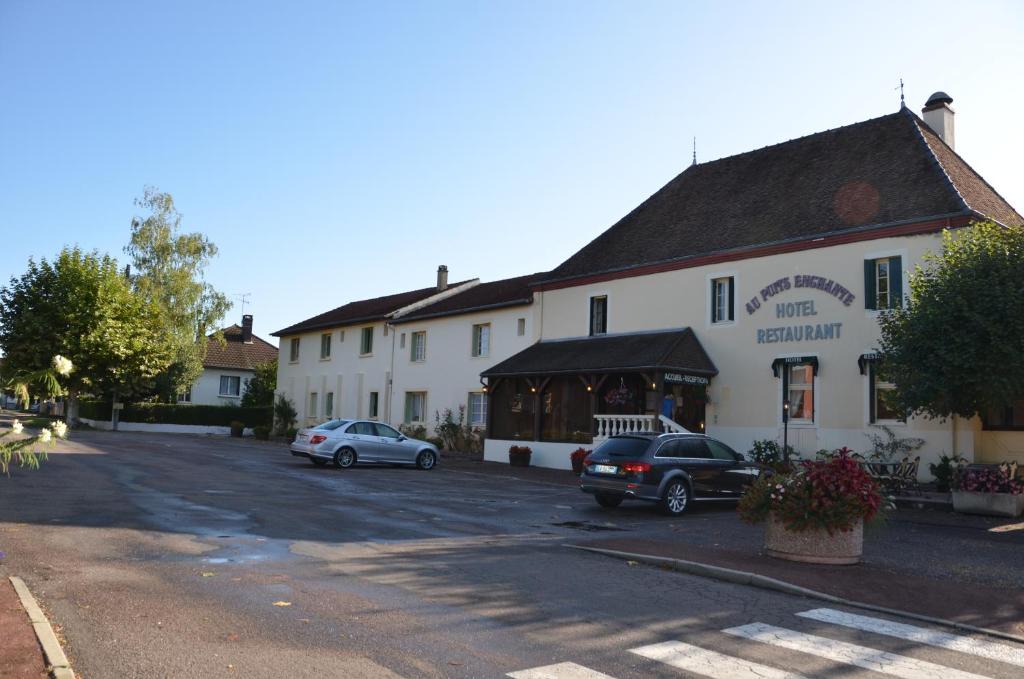 een groot wit gebouw met auto's geparkeerd op een parkeerplaats bij Au puits enchanté in Saint-Martin-en-Bresse