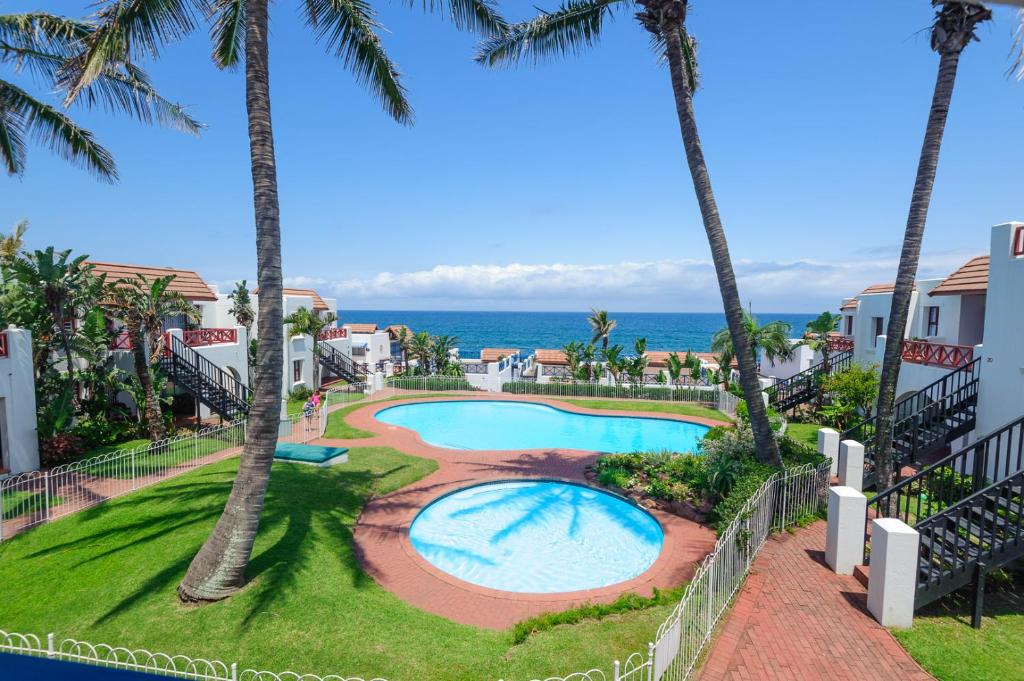 a view of the pool and ocean from the balcony of a resort at Le Paradis 5 - With Inverter in Ballito