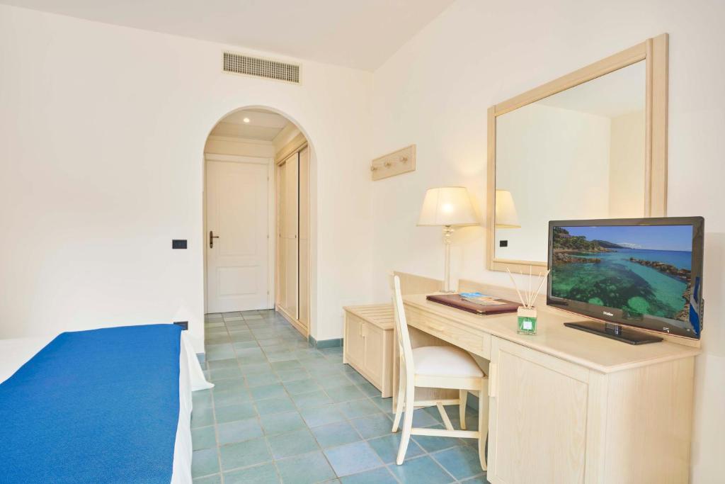 a bedroom with a desk with a television and a bed at Hotel Biodola in Portoferraio