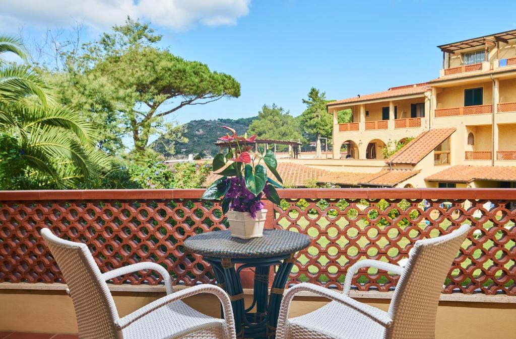 a table with chairs and a vase of flowers on a balcony at Hotel Biodola in Portoferraio