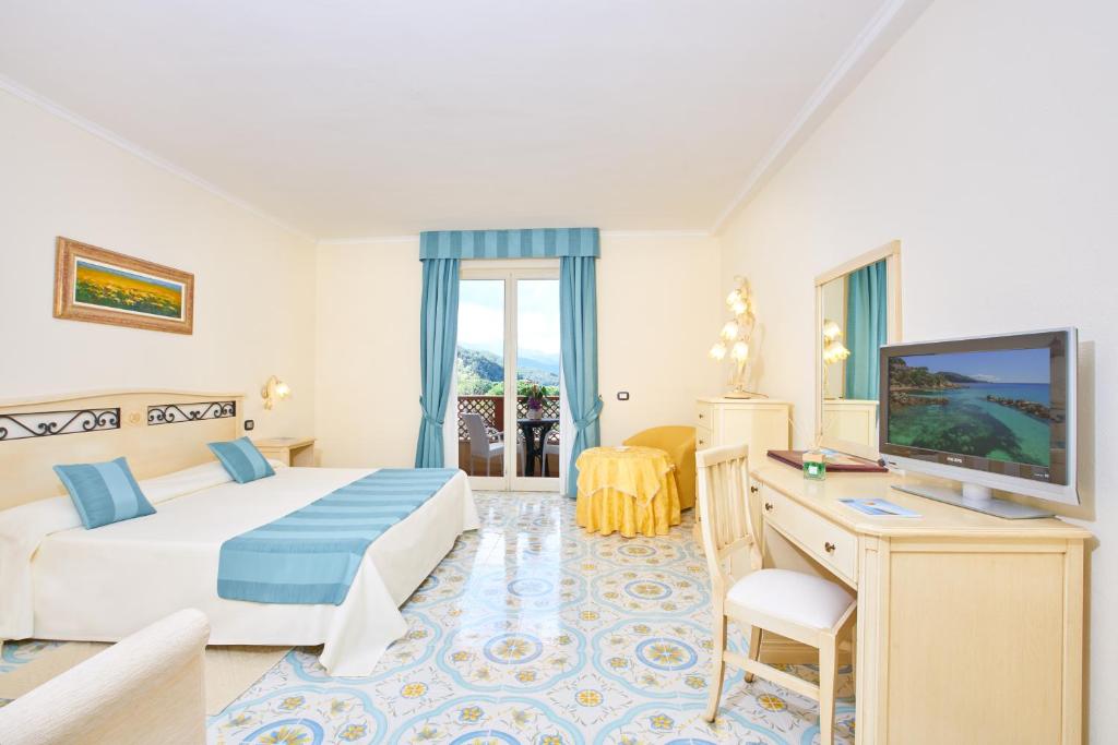 a hotel room with a bed and a desk and a television at Hotel Biodola in Portoferraio