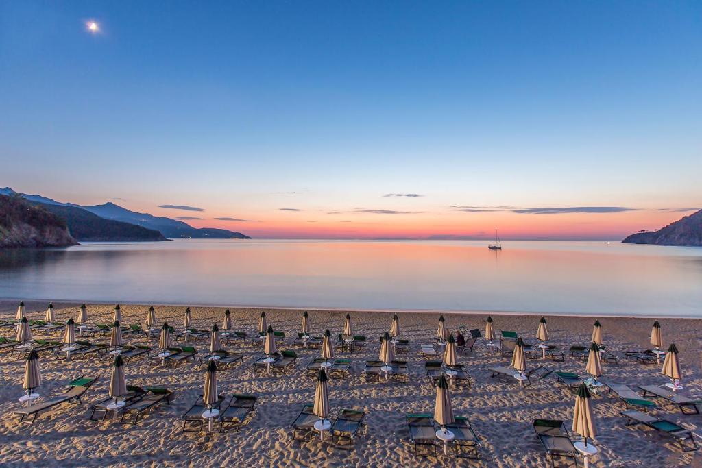 een groep parasols en stoelen op een strand bij Hotel Biodola in Portoferraio