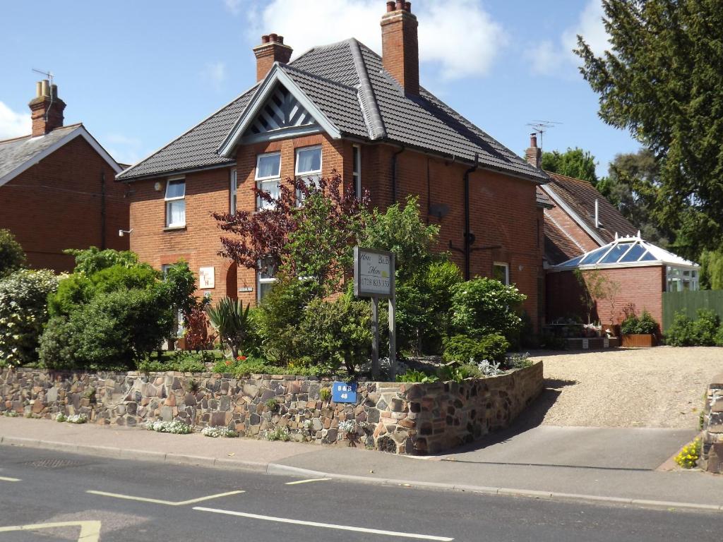 a red brick house with a sign in front of it at Home from Home Guesthouse in Leiston