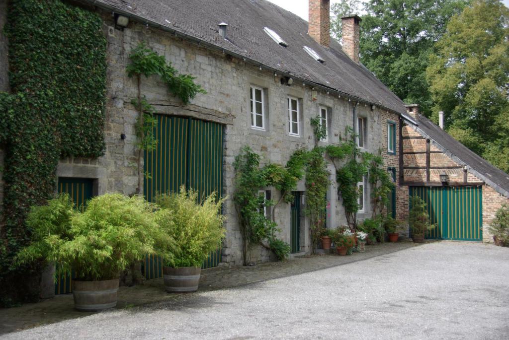 an old stone building with green doors and plants at B&B Le Moulin de Resteigne in Resteigne