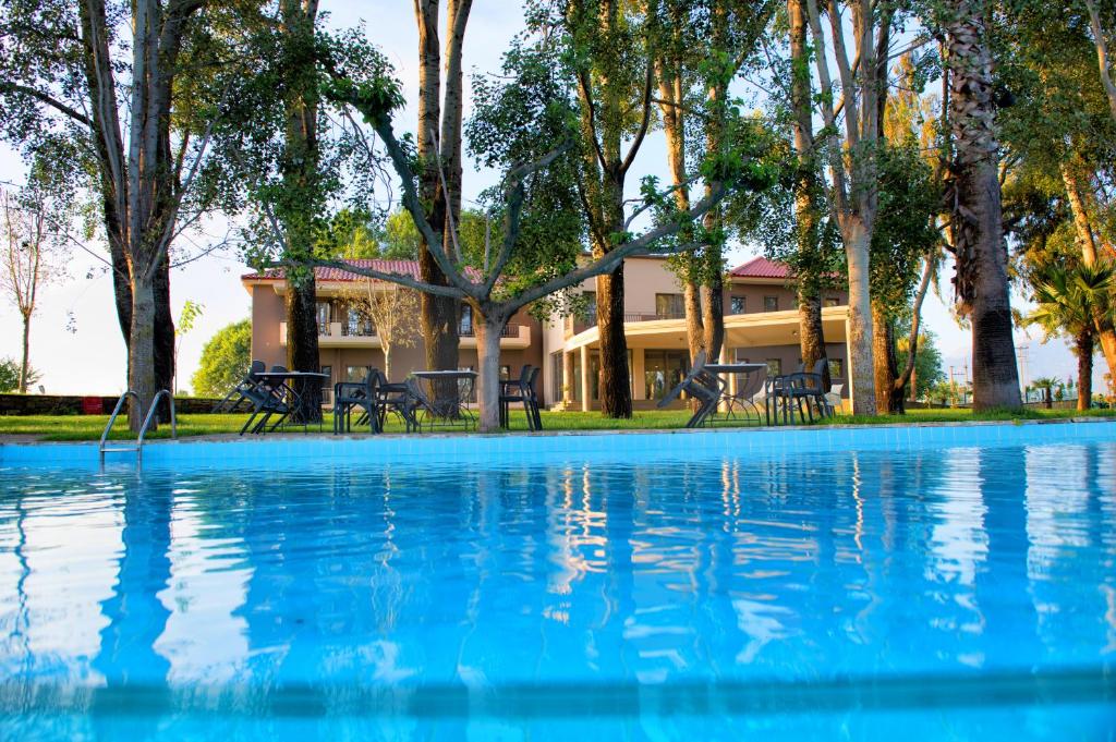 a large swimming pool with a house in the background at Corali Resort in Agrinion