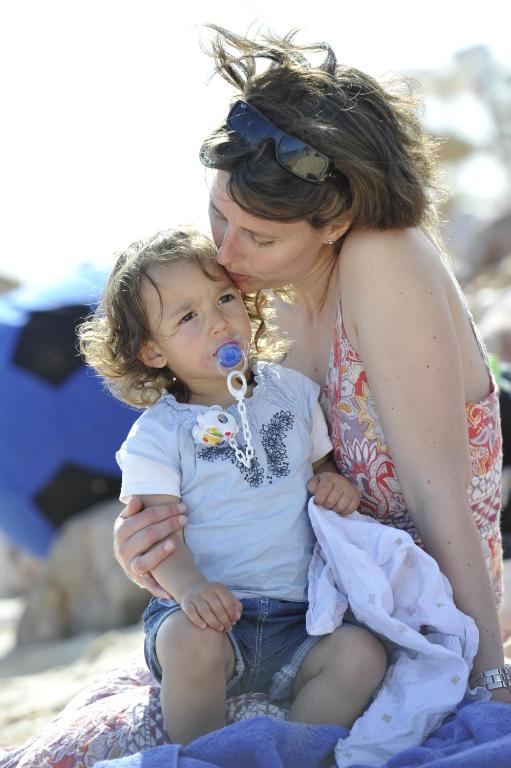 a woman holding a child on the beach at Martinhal Sagres Beach Family Resort Hotel in Sagres