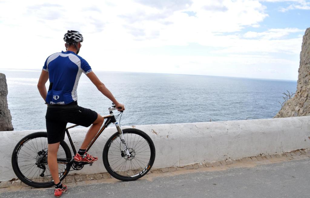 a man riding a bike near the ocean at Martinhal Sagres Beach Family Resort Hotel in Sagres