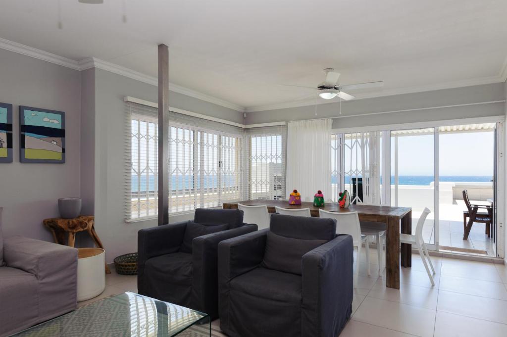 Una sala de estar con una mesa y sillas y el océano. en Vallen Lodge 2 With Inverter, en Ballito