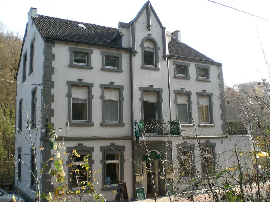 a white house with a black roof at Hotel Bergische Schweiz in Velbert