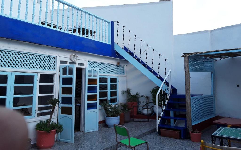 un edificio con una escalera azul y una silla verde en White And Blue, en Essaouira