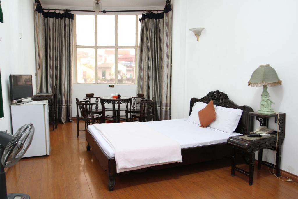 a bedroom with a bed and a table with chairs at Hoang Cuong Hotel in Hanoi